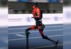 Red humanoid robot running on an indoor track at the 2026 World Humanoid Robot Games in Beijing