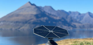 Iris T1 portable solar generator with its tracking panel facing the sun beside a mountain lake