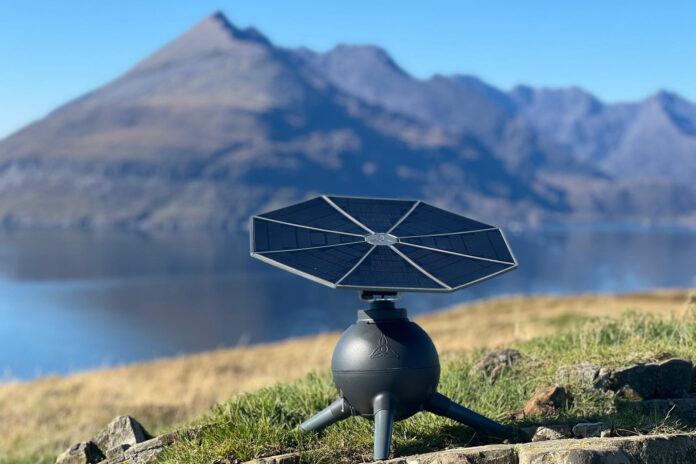Iris T1 portable solar generator with its tracking panel facing the sun beside a mountain lake