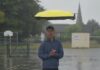 John Xu standing in heavy rain beneath his autonomous flying drone umbrella