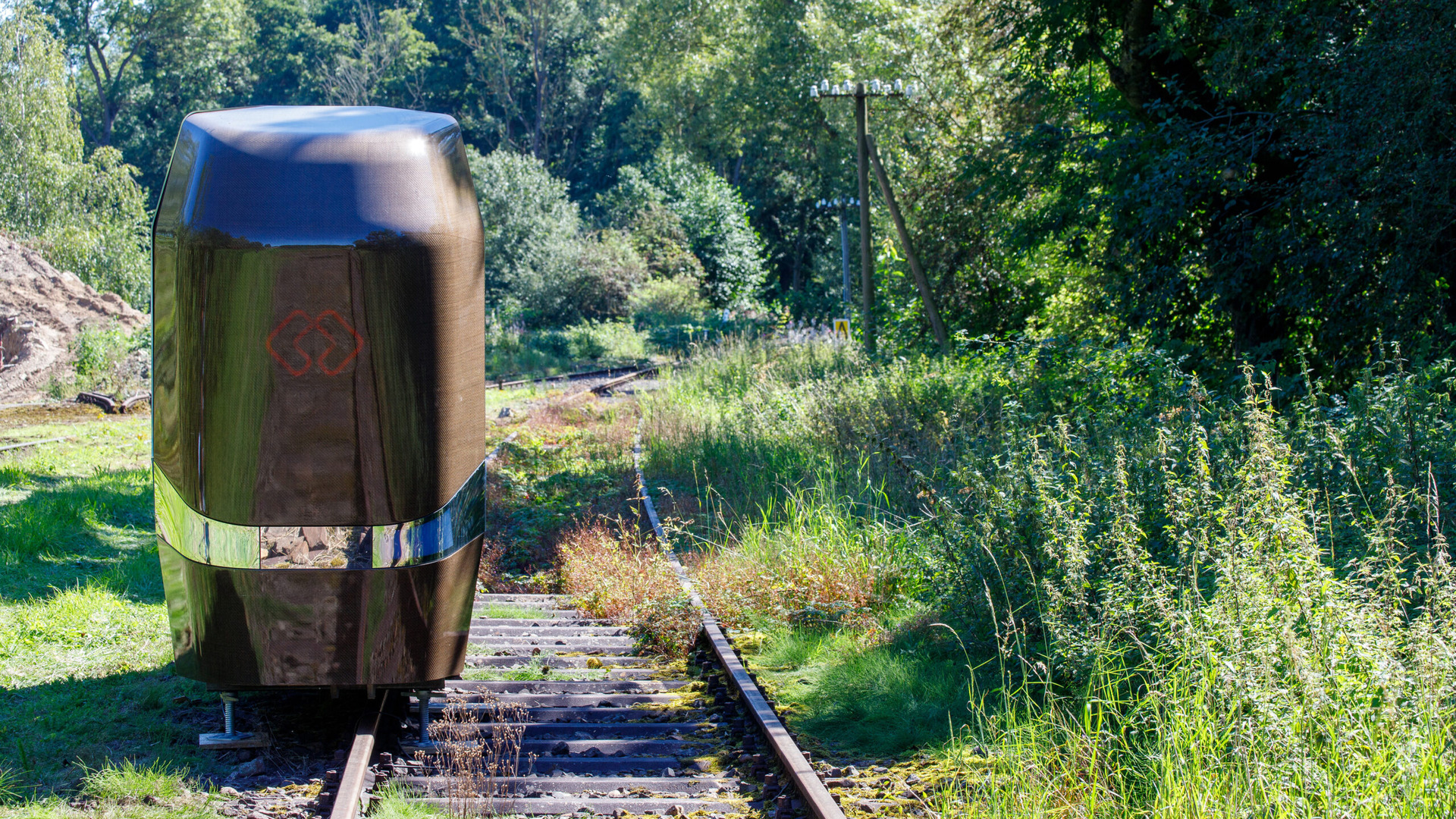 MONOCAB cabin design demonstrator standing on one rail of a rural railway track