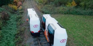 MONOCAB electric monorail cabins travelling on a rural railway track