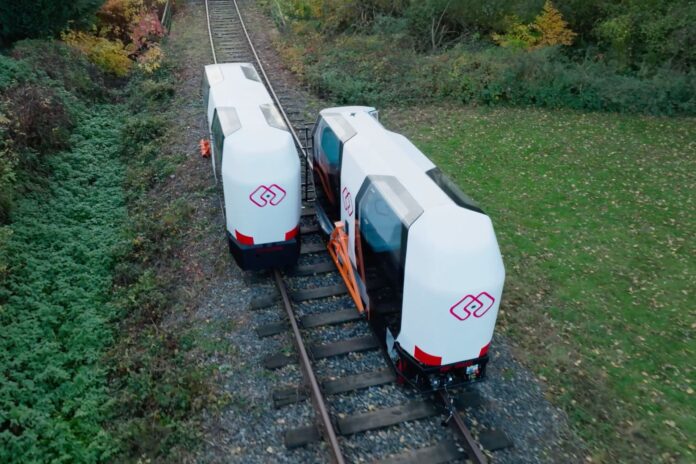 MONOCAB electric monorail cabins travelling on a rural railway track