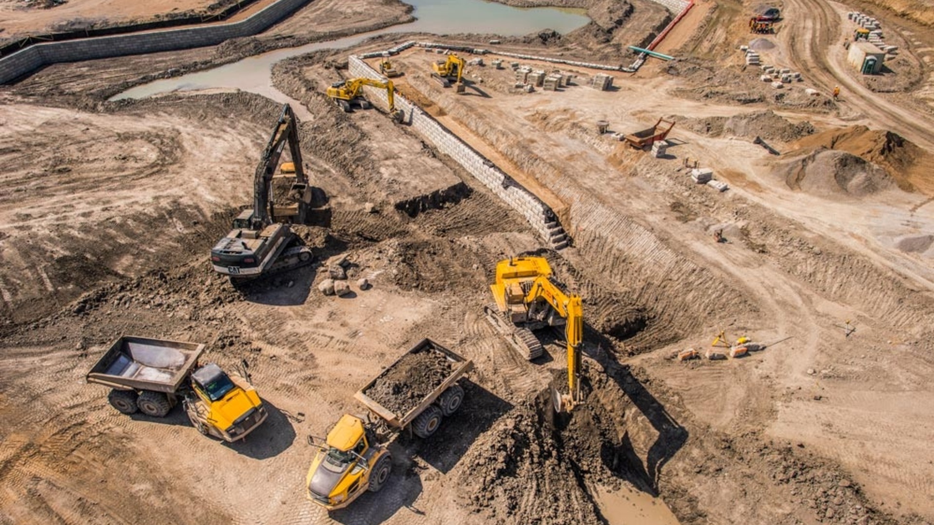 Excavators constructing a large Redi-Rock retaining wall at an earthworks site