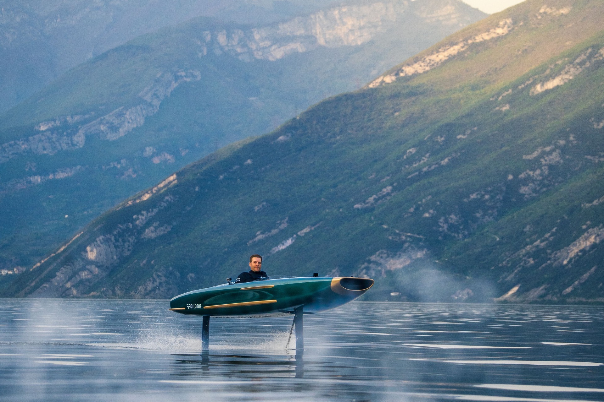 Foilone Pegasus electric boat foiling on calm water below mountains