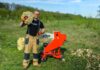 Operator standing beside the red ARPAL Classic AM-80BD wood chipper and bags of cut wood