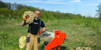 Operator standing beside the red ARPAL Classic AM-80BD wood chipper and bags of cut wood