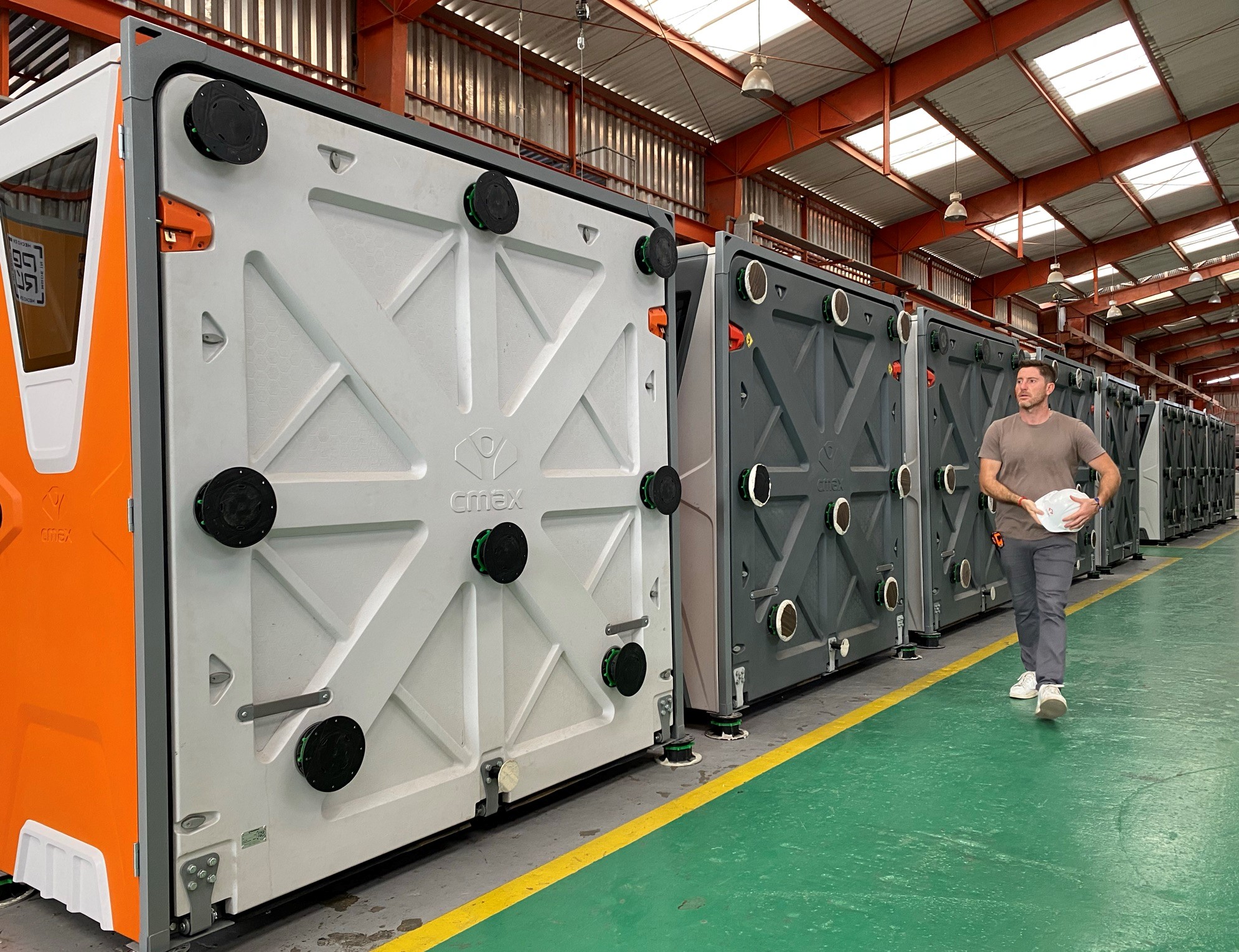 Row of folded white, orange and gray CMAX shelter units inside a warehouse