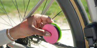 A cyclist holding the Green Disc+ applicator against a bicycle chain while turning the crank
