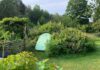 Green Groundfridge entrance surrounded by flowers and plants in a landscaped garden