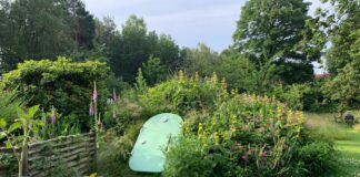 Green Groundfridge entrance surrounded by flowers and plants in a landscaped garden