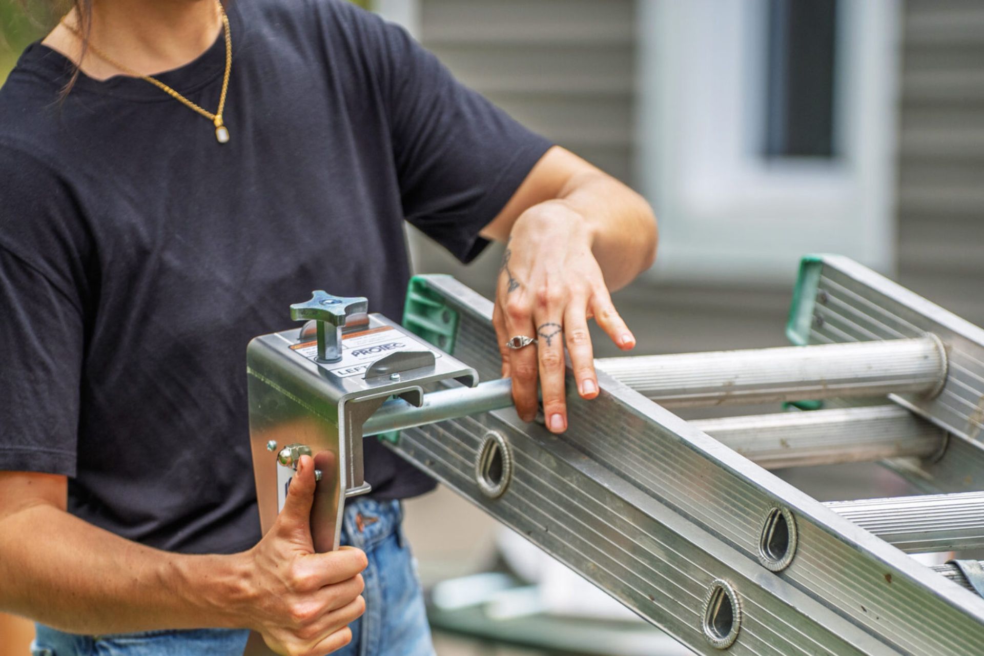 Person installing a ProtecMi stabilizer arm into an open extension-ladder rung