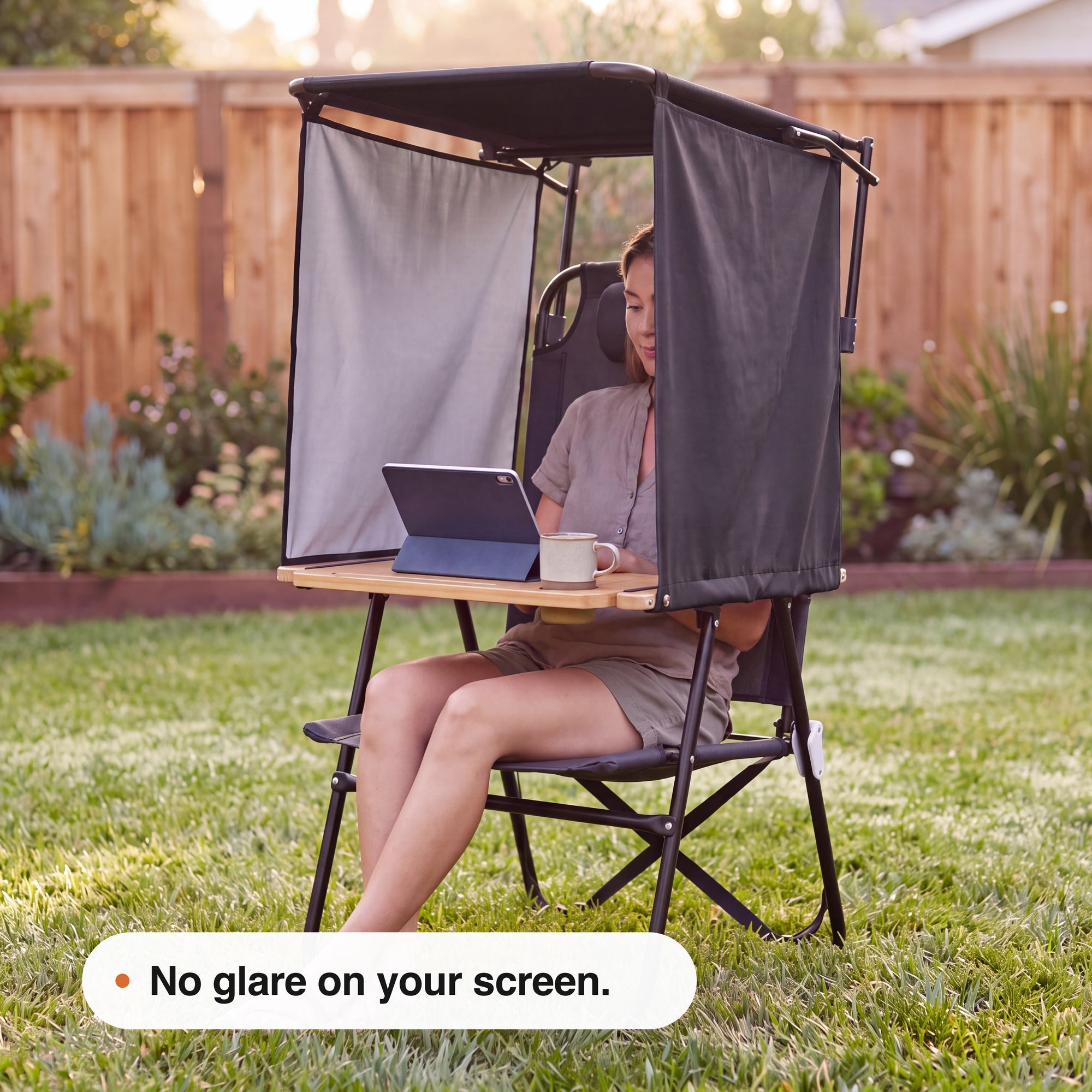 Person using a laptop while seated inside a NomaPod outdoor workstation in a garden