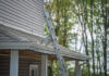 Extension ladder fitted with two ProtecMi stabilizer arms resting on a shingle roof