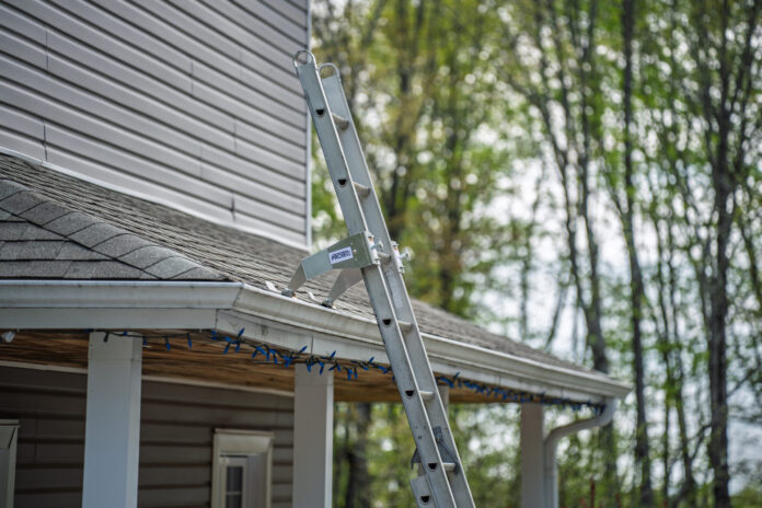 Extension ladder fitted with two ProtecMi stabilizer arms resting on a shingle roof