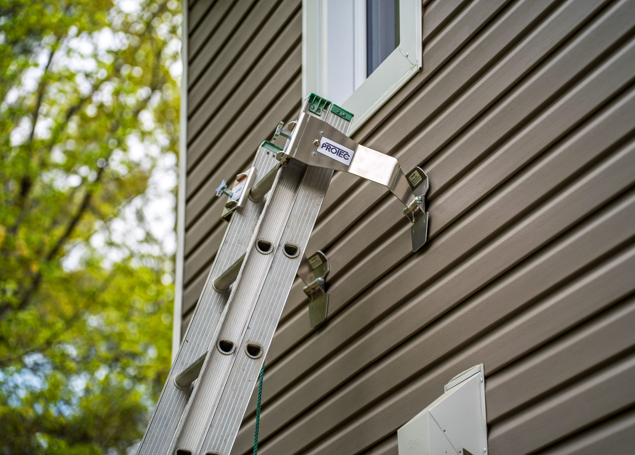 ProtecMi residential stabilizers holding an extension ladder away from vinyl siding