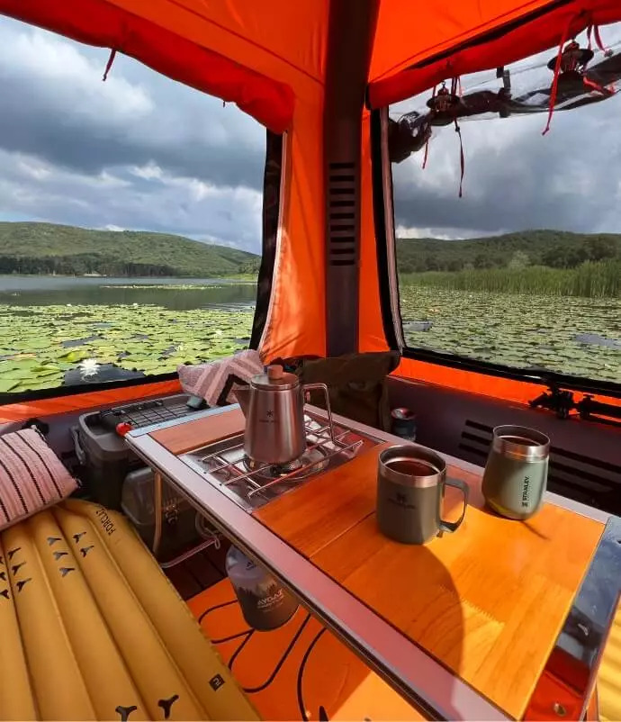 Interior of the orange Sönmez Floating Tent with seating, a table and large screened windows