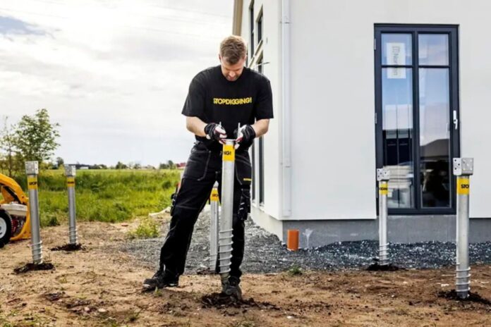 Installer positioning a galvanized StopDigging ground screw beside a modular building
