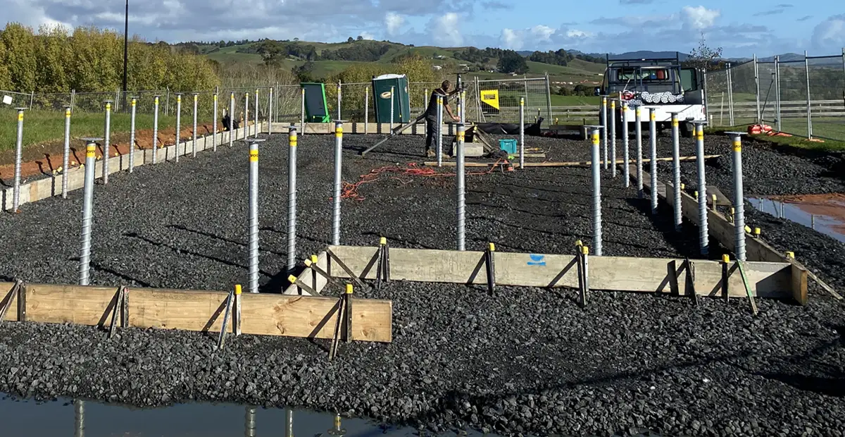 Rows of galvanized ground screws installed within a prepared concrete slab foundation