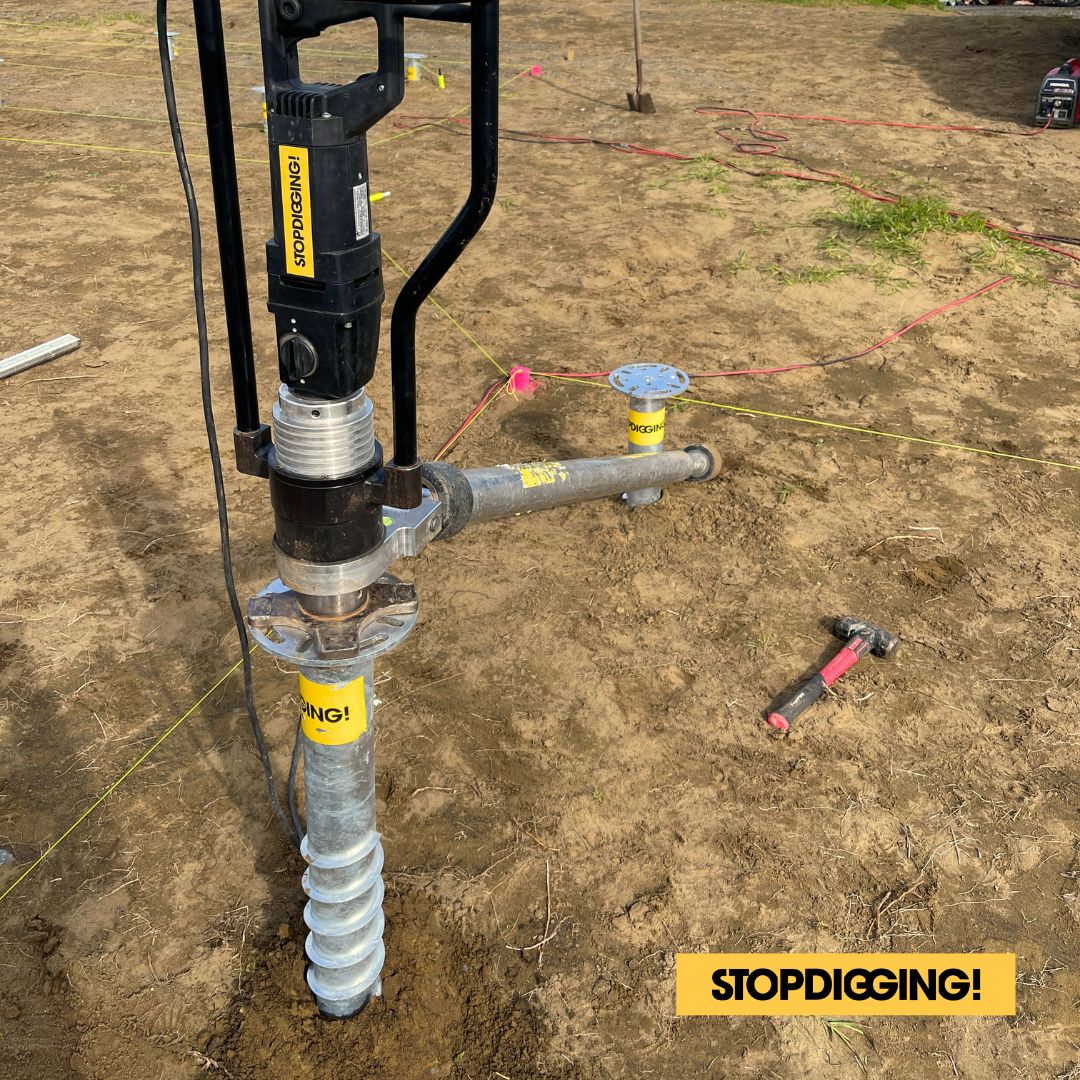 Close-up of an installation machine driving a StopDigging SGC ground screw into soil