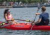 Two people facing each other in a red RowYak on a lake