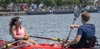Two people facing each other in a red RowYak on a lake