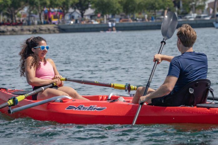 Two people facing each other in a red RowYak on a lake