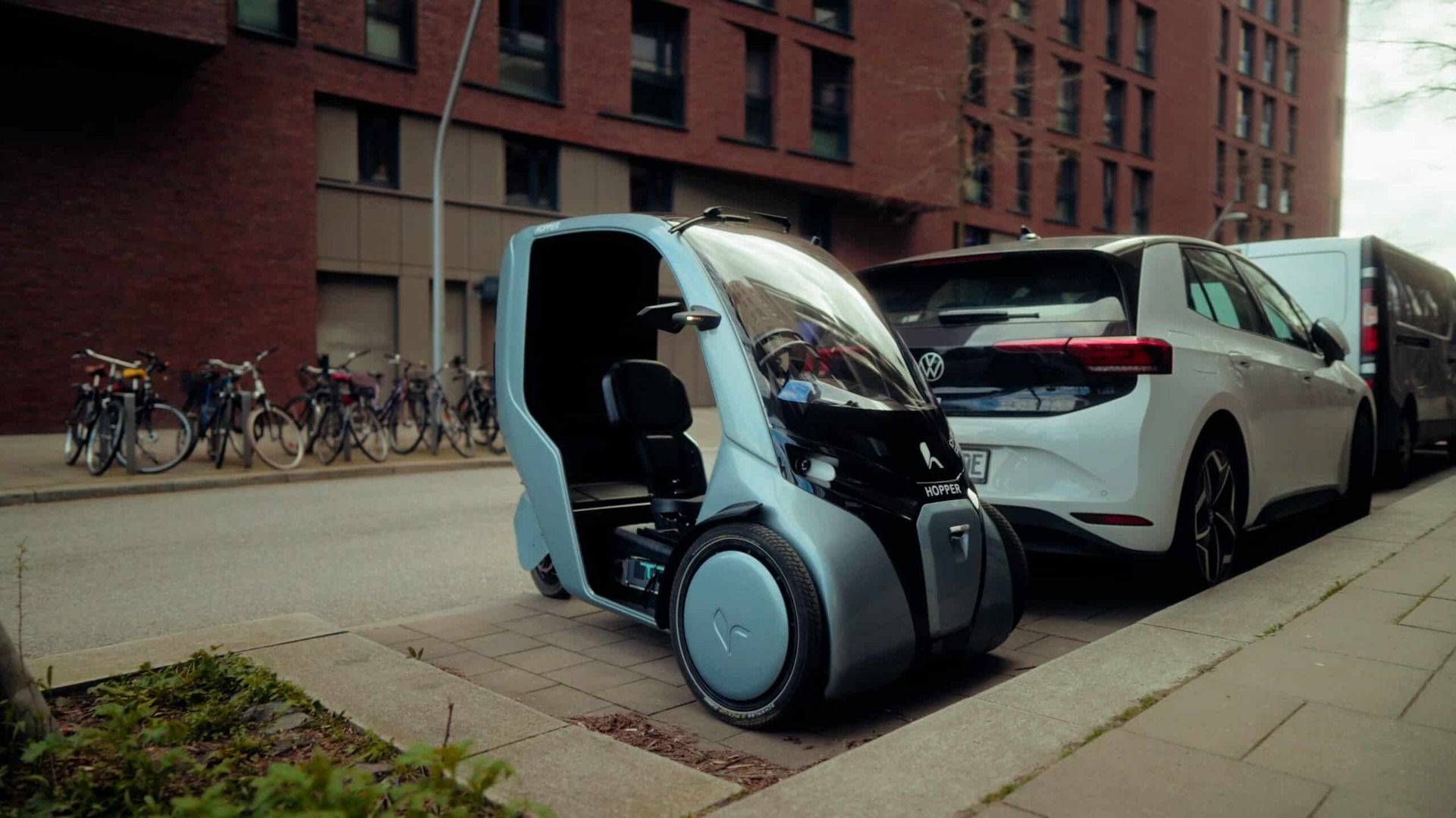 Compact HOPPER electric cargo bike parked beside a conventional passenger car