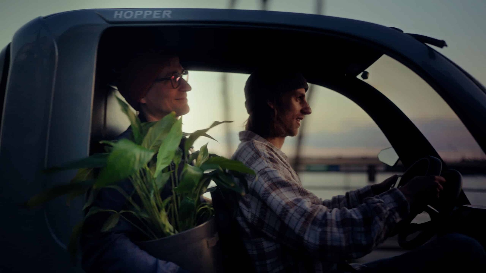 Two adults riding together inside a green HOPPER Passenger electric cargo bike