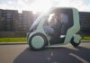 Green HOPPER weather-protected electric cargo bike traveling on a city street