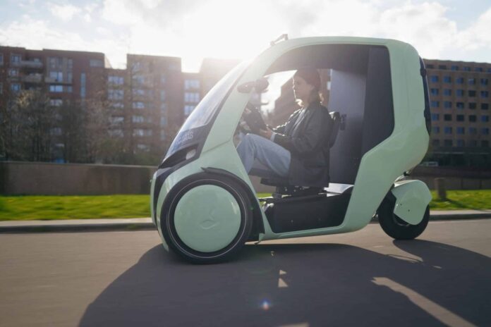 Green HOPPER weather-protected electric cargo bike traveling on a city street