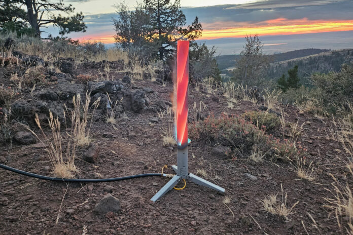 Happy Caveman propane campfire glowing red on rocky ground at sunset